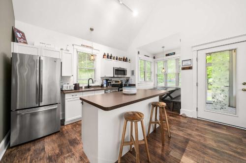 a kitchen with white walls and a stainless steel refrigerator at The Trillium - 2 Pine Forest in Cherry Valley
