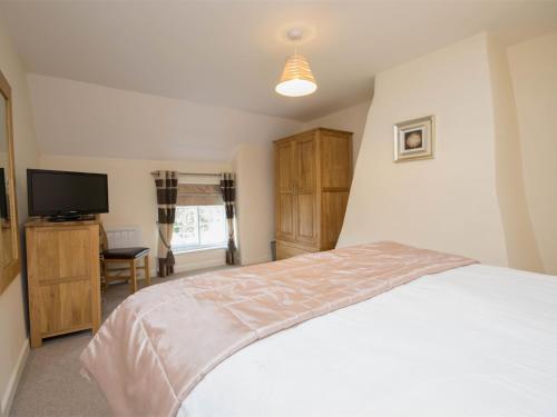 a bedroom with a bed and a flat screen tv at 1 Bed in Wool DC153 in Wool