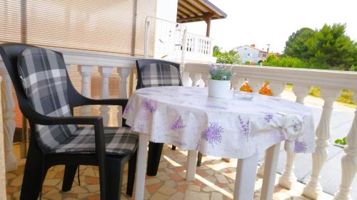 a table and two chairs on a porch with a table and flowers at Apartment Zdravko in Štinjan