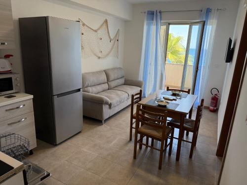een woonkamer met een koelkast en een tafel met stoelen bij FAMILY HOUSE Letojanni Taormina in Letojanni