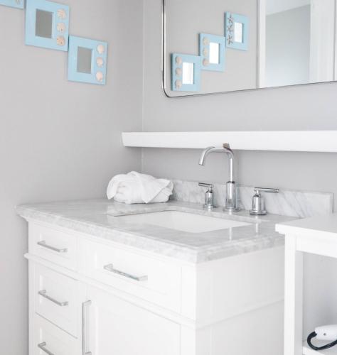 a white bathroom with a sink and a mirror at Driftwood Resort on the Ocean in Montauk