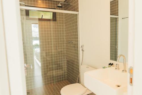 a bathroom with a shower and a toilet and a sink at Wyndham Ilhabela Casa Di Sirena in Ilhabela