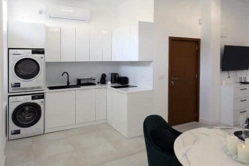 a white kitchen with a sink and a washing machine at Студио in Burgas City