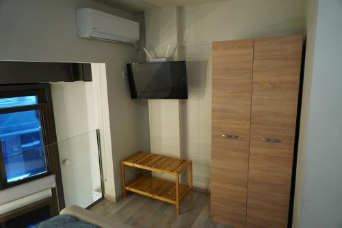 a small room with a television and a wooden cabinet at Karditsa's Loft House in Kardítsa