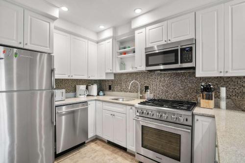 a kitchen with white cabinets and a stainless steel refrigerator at Charming Getaway 1 Block from Beach in Provincetown