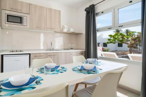 a kitchen and dining room with a white table and chairs at Apartamentos Santa Rosa in Costa Teguise