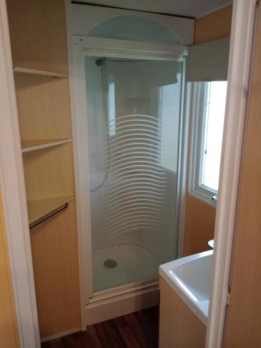 La salle de bains est pourvue d'une douche en verre et d'un lavabo. dans l'établissement mobil home 4 personne 2 chambre vu lac a condes, à Condes
