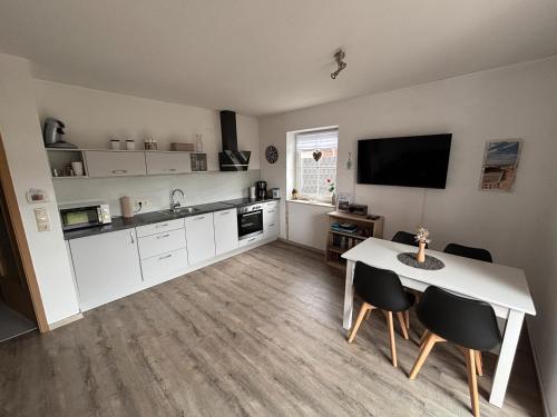 a kitchen with a table and chairs and a television at Ferienwohnung Charly in Carolinensiel