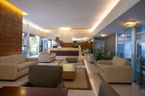 a living room with couches and tables and windows at Arituba Park Hotel in Natal