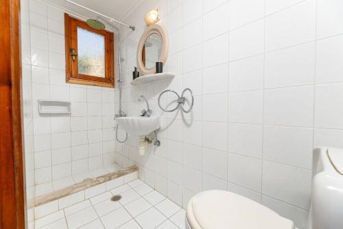a white bathroom with a toilet and a sink at Lyria Hotel Apartments in Stalos