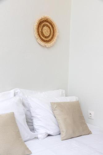 a white bed with white pillows and a hat on the wall at Lyria Hotel Apartments in Stalos