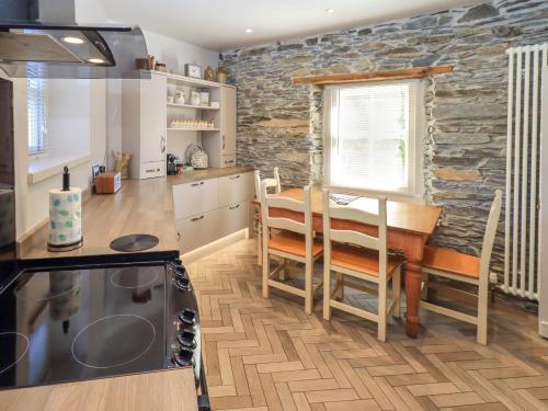 a kitchen and dining room with a table and a stone wall at Bridge End Cottage in Ulverston