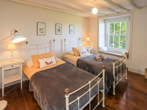 a bedroom with two beds and a window at Bridge End Cottage in Ulverston