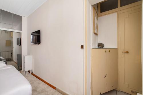 Cette chambre blanche dispose d'un lit et d'une porte. dans l'établissement Paris Marais Ste Catherine, à Paris