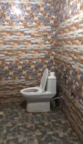 a bathroom with a toilet and a wall of tiles at Marongs Appartment in Djalabango