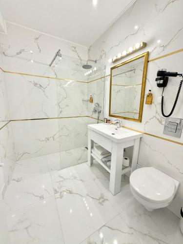 a white bathroom with a sink and a toilet at Krystal Boutique Mansion in Hunedoara