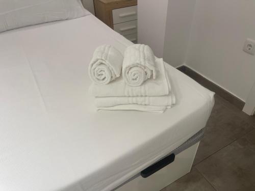 a bed with white towels sitting on top of it at Apartamentos Palma del Río CAROLA in Linares