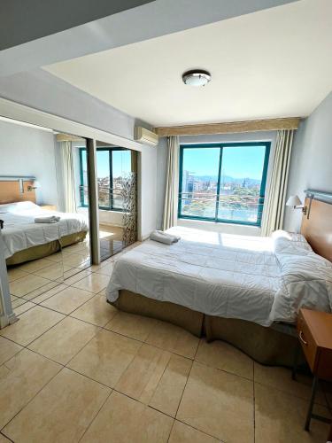 a bedroom with two beds and a large window at Precioso departamento en la mejor ubicación de Ciudad Mendoza, con piscina in Mendoza