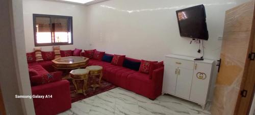 a living room with a red couch and a flat screen tv at YOUEL2 Appartments in Martil