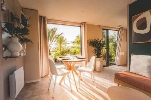 Una sala de estar con una mesa y sillas y una gran ventana. en Camping 3 étoiles - Piscine - eec0di, en Fouesnant