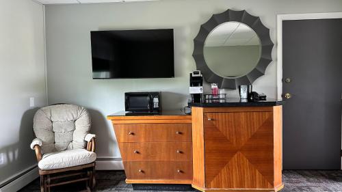 a bedroom with a dresser with a mirror and a chair at Colonial Valley Motel in Farmington