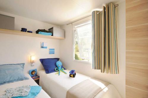 a bedroom with a bed with a toy on it at Camping 4 étoiles - Parc aquatique - eeia0i in Le Bois-Plage-en-Ré