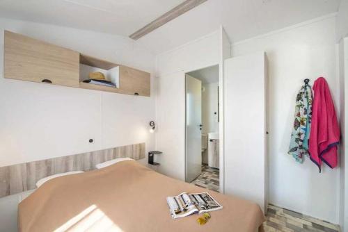 a white room with a bed and a mirror at Camping 5 étoiles - Parc aquatique - eeiade in Brem-Sur-Mer