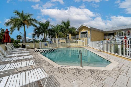 una piscina con sedie bianche e una casa di Harbour House at the Inn #308 a Fort Myers Beach