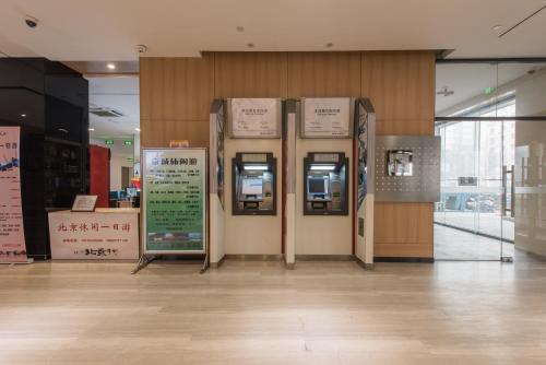 an atm machine in a building with signs on the wall at IU Hotel Beijing West Coach Station Liuliqiao East Metro Station in Beijing