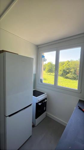 une cuisine avec un réfrigérateur blanc et une fenêtre dans l'établissement Magnifique appartement moderne 3 chambres, à Montréjeau