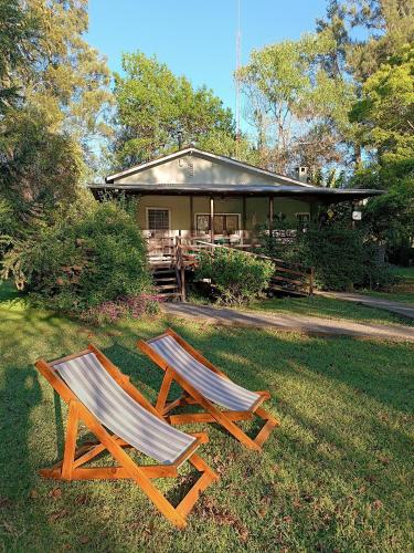 two chairs sitting in the grass in front of a house at Quinta Las Marías - Domingos Check out 17 hs in Tigre
