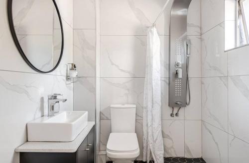 a bathroom with a toilet and a sink and a mirror at Cozy loft with swimming pool in Johannesburg