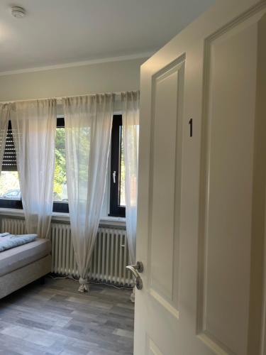 a room with a window with white curtains and a door at Cozy Private Rooms in Wesseling in Wesseling