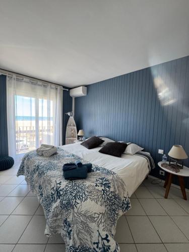 une chambre avec un grand lit avec un mur bleu dans l'établissement Front de mer 100m2 Vue magnifique, balcon, jardin, garage, à Valras-Plage