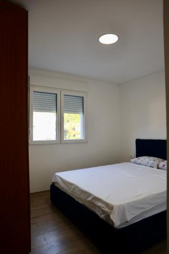 a bedroom with a bed and two windows at Little Sunshine in Herceg-Novi