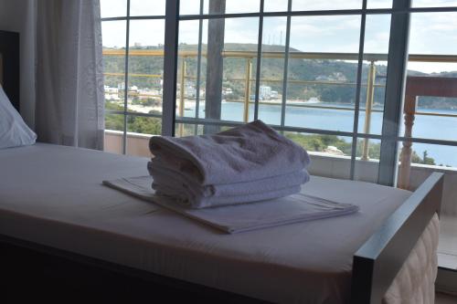una pila de toallas sentadas en una cama con ventana en Ionio Rooms II, en Himare