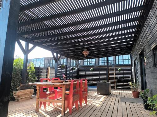 a patio with a wooden table and red chairs at SirenaHouse, Casa a metros del Mar in De Cauquenes