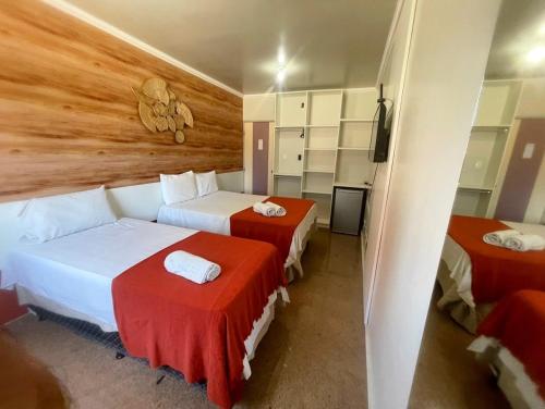 a hotel room with two beds and a television at Pousada Maré Alta em Pajuçara in Maceió