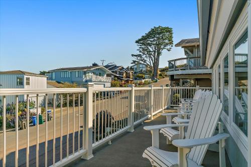 a balcony with white chairs on a house at Cape Cod Charm By The Sea in Cambria