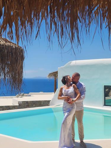 a bride and groom kissing next to a swimming pool at ELLI TROPiCAL LUXURY SUITES SUNSET-INFINITY POOL- SEA SIDE-NEAR CENTER PARKING in Mikonos