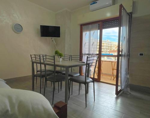 a dining room with a table and chairs and a balcony at CAMI MARE BLU Apartment - Steps from the Sea 50mt & Train and Bus Station in Nettuno