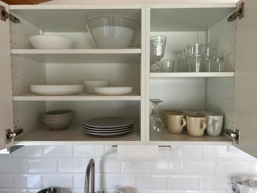 a kitchen cabinet filled with plates and bowls and dishes at Przystań Ogrodowa Mikołajki in Mikołajki