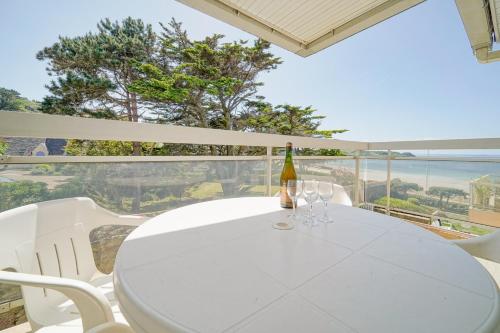 a white table and chairs with a bottle of wine at Granit & Vagues - Balcon vue mer, séjour à Trébeurden, front de mer in Trébeurden