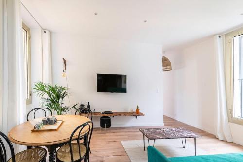 un salon avec une table et une télévision au mur dans l'établissement LX151 Calme confort & style en coeur de ville, à Menton