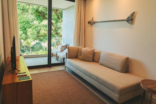 a living room with a couch and a window at Wyndham Ilhabela Casa Di Sirena in Ilhabela