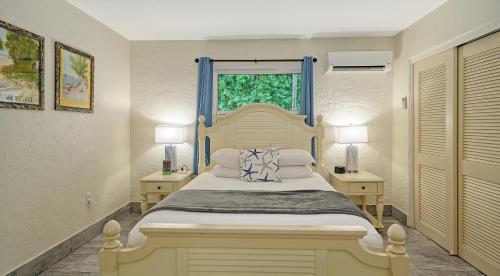 a bedroom with a large bed with a window and two tables at Siesta Key Palms Resort in Sarasota