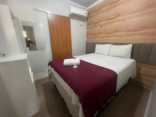 a bedroom with a large bed with a purple blanket at Pousada Maré Alta em Pajuçara in Maceió