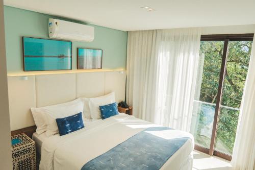 a bedroom with a large bed and a window at Wyndham Ilhabela Casa Di Sirena in Ilhabela