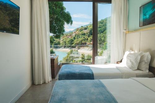 a hotel room with two beds and a large window at Wyndham Ilhabela Casa Di Sirena in Ilhabela