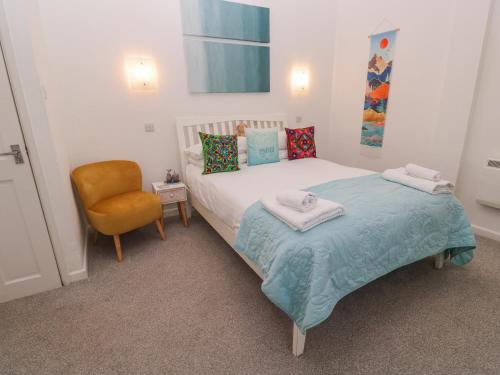 a small bedroom with a bed and a chair at Beachcomber in Marazion